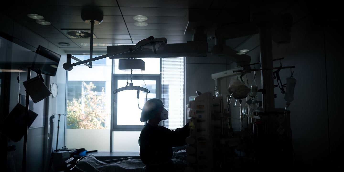 Eine Mitarbeiterin der Pflege steht in einem Zimmer einer Corona-Intensivstation.